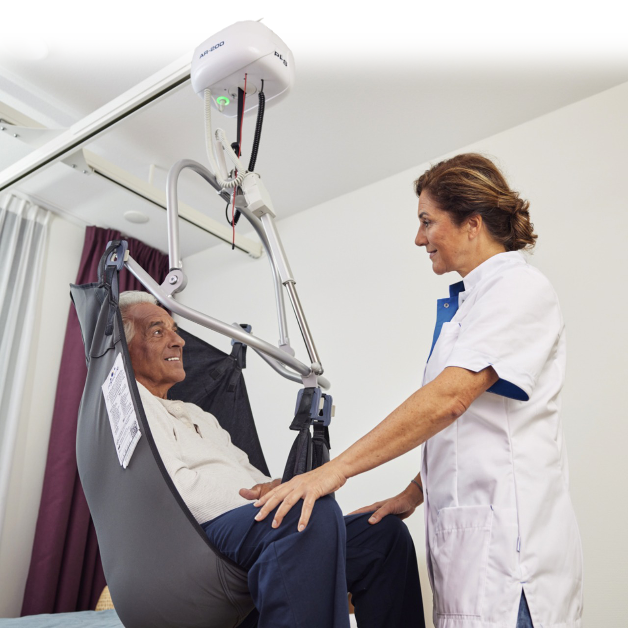 Caregiver looking at man being transfered with PLS Ceiling Lift